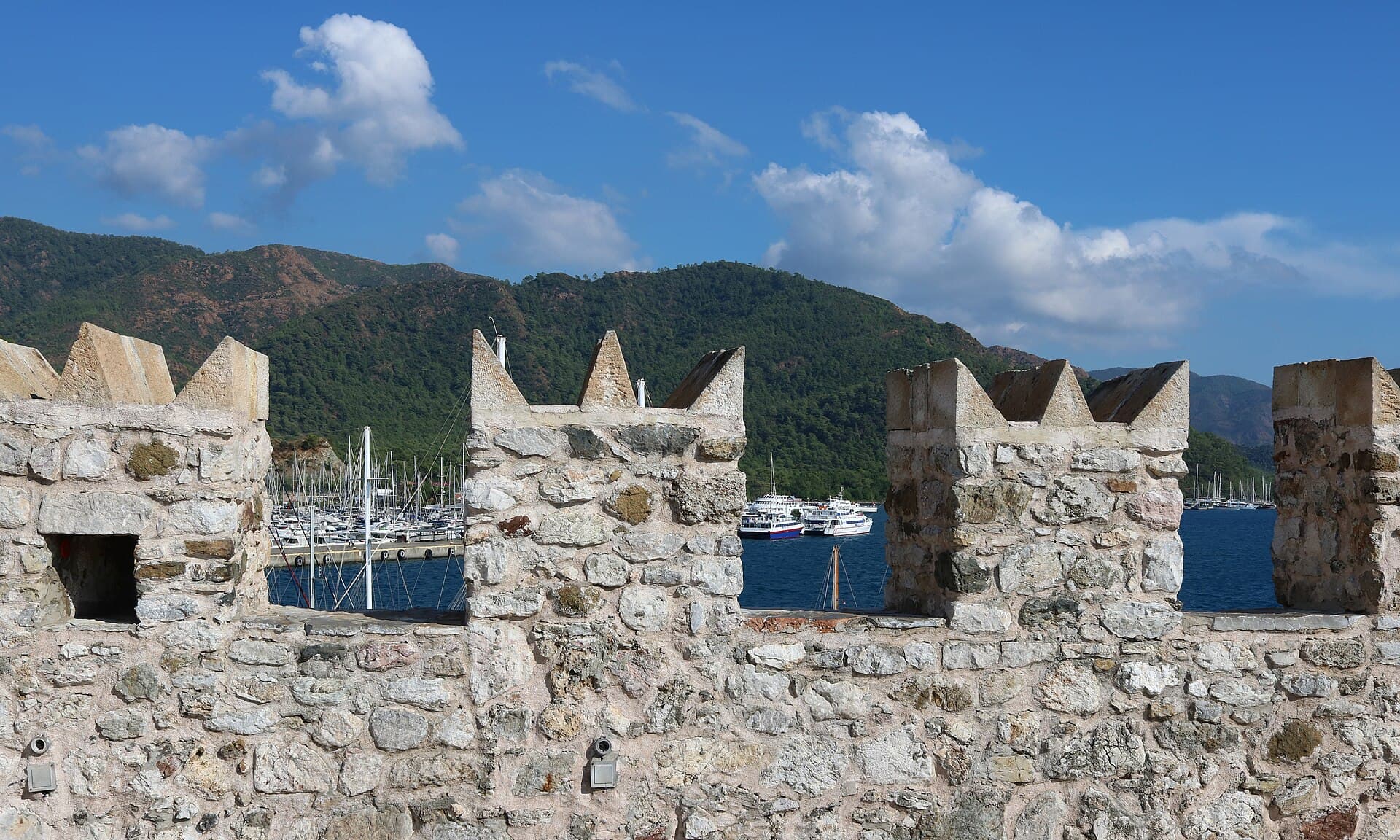 The marina and wooded hills of Marmaris seen between the battlements of the castle