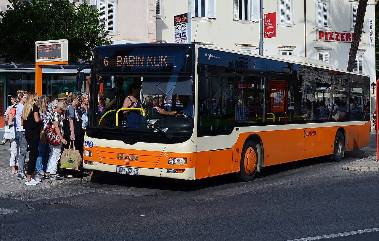 An orange Libertas bus at a stop in Dubrovnik, signed for Babin Kuk