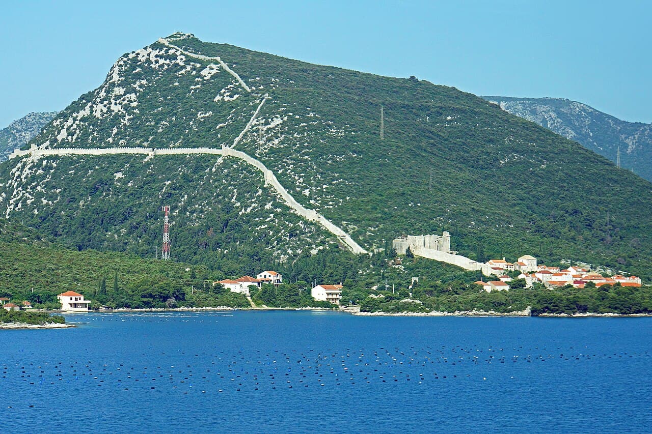 The walls of Ston climbing the green hillside above the village and the sea