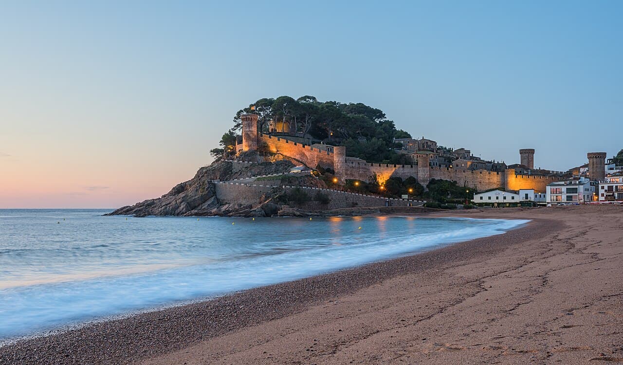 The lit walls and towers of the Vila Vella above the beach at Tossa de Mar