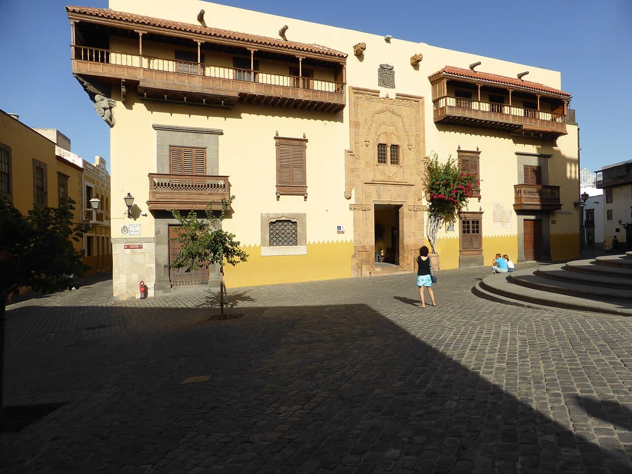 The yellow and white façade of the Casa de Colón museum in Vegueta, with its wooden balconies