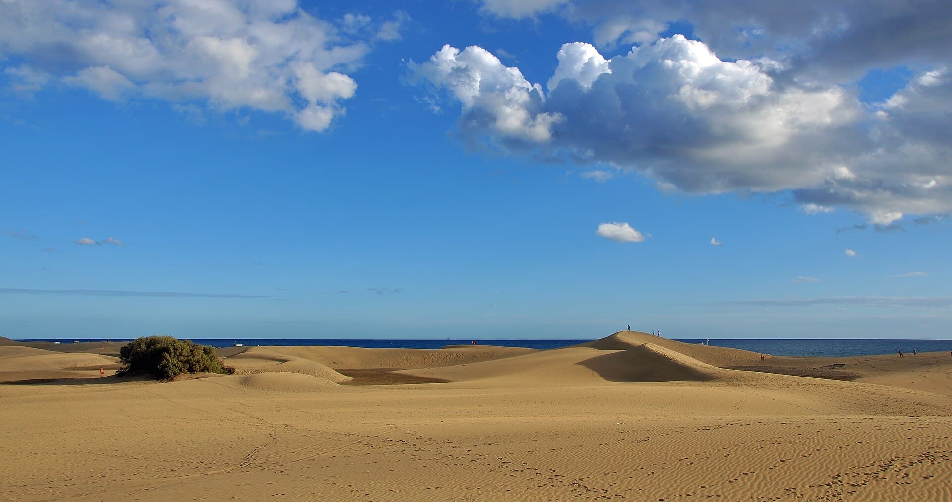 The Maspalomas Dunes running down to the Atlantic under a blue sky with white clouds