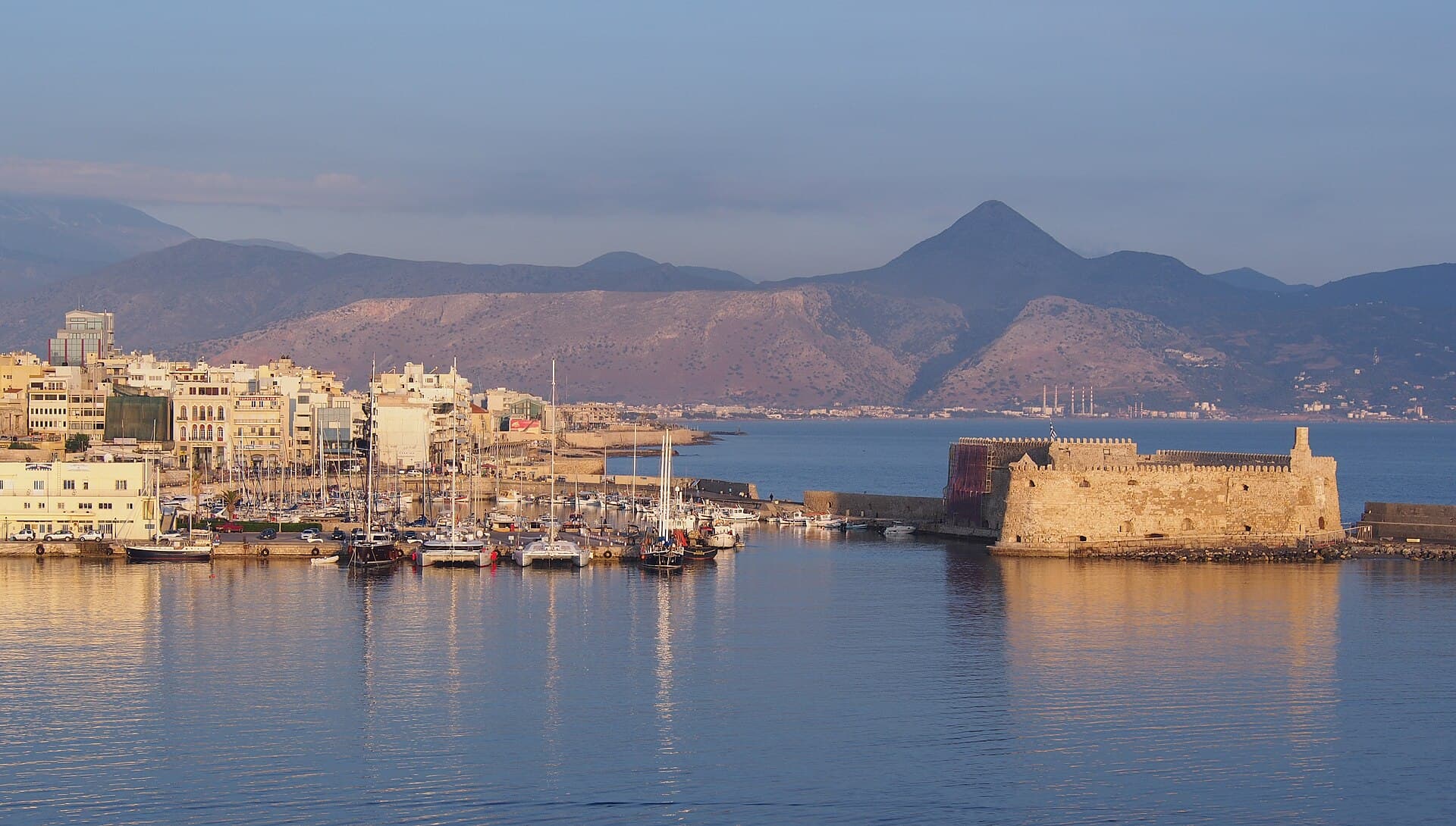 Heraklion’s old harbour and the Koules fortress in the evening light, with mountains behind