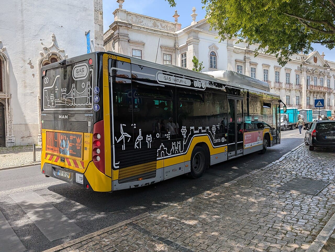 A yellow Carris city bus at a stop in central Lisbon