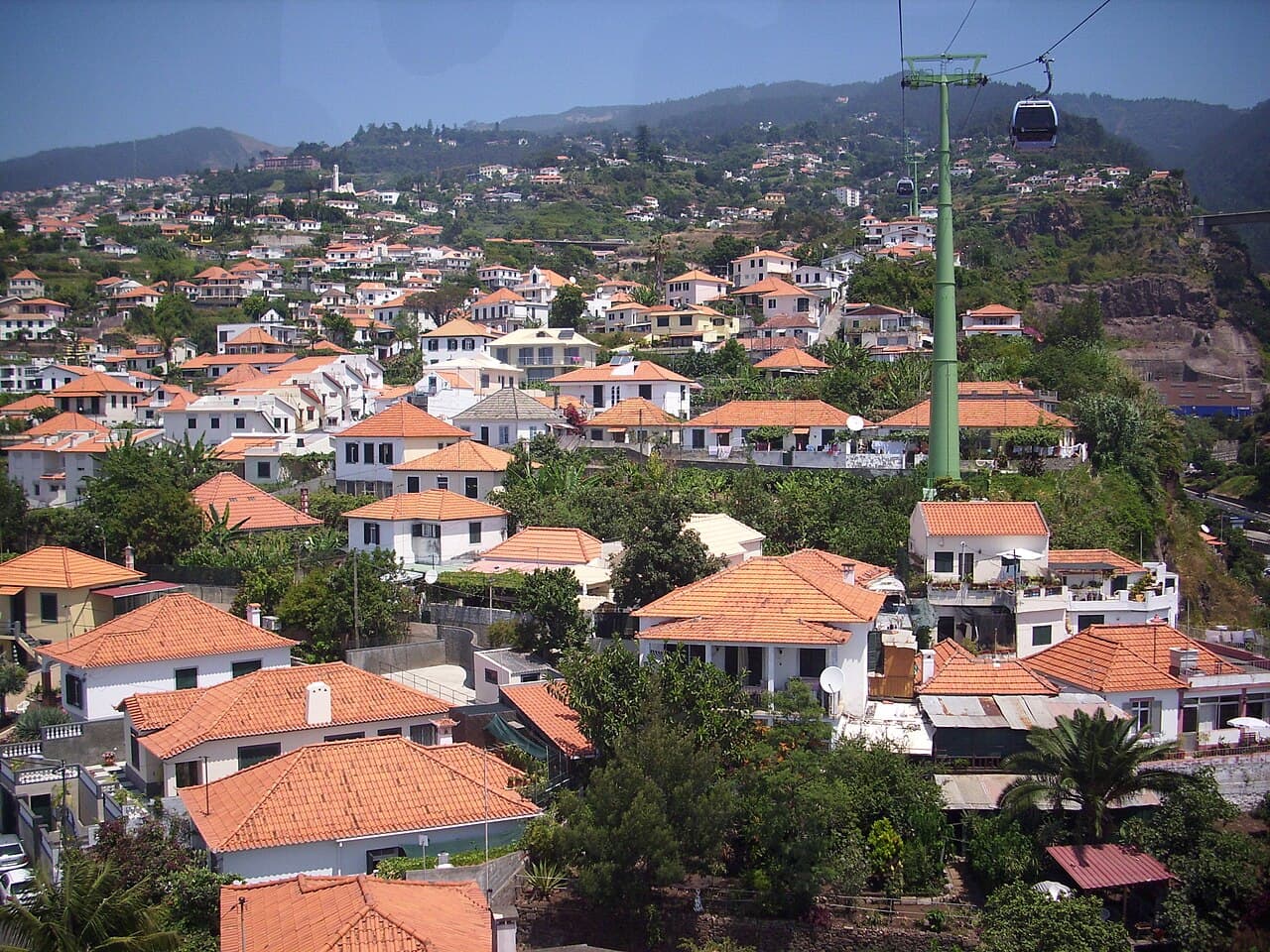 Cable car cabins above the red-tiled roofs of Monte, with Funchal below