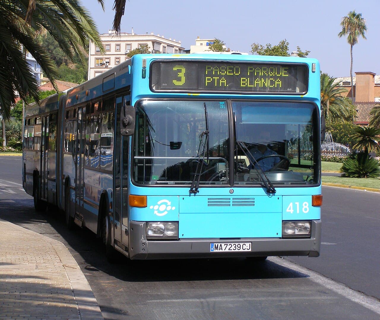 An articulated EMT Málaga city bus on a sunny street in Málaga