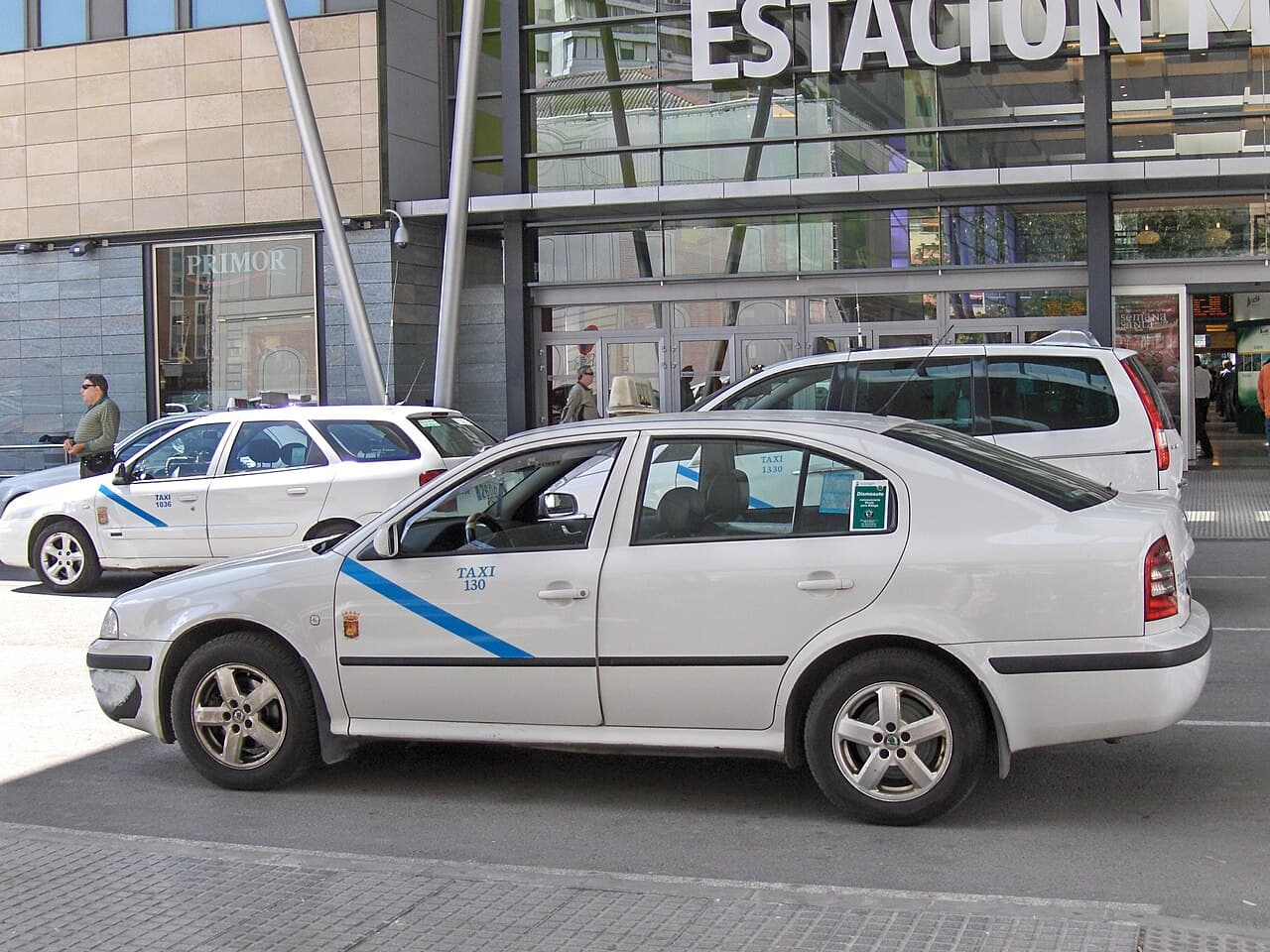 White Málaga taxis with a blue stripe waiting outside a station
