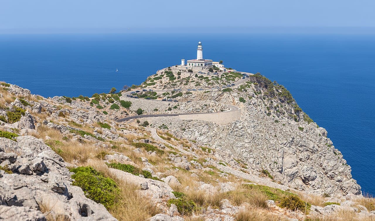 The Formentor lighthouse on the rocky ridge of the cape above a deep-blue sea