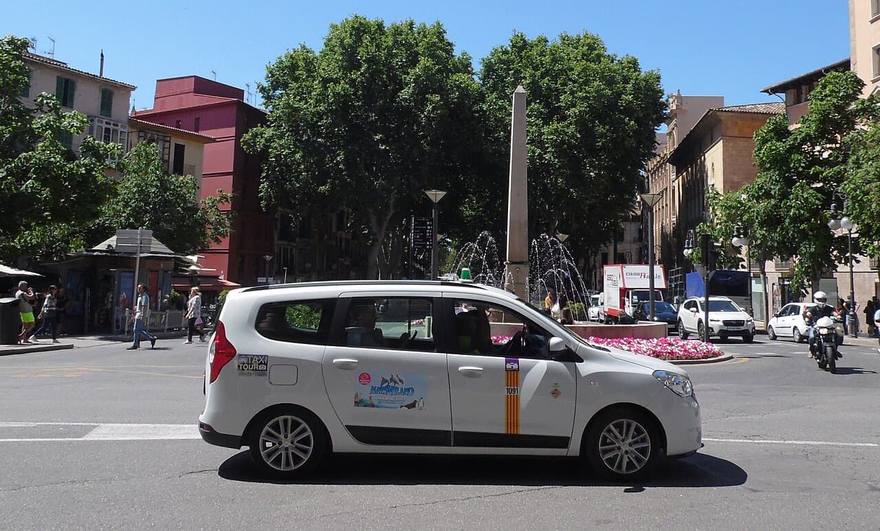 A white Palma taxi crossing Plaça de les Tortugues in the city