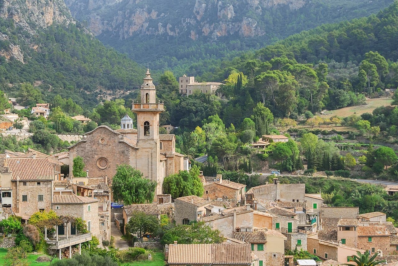 The stone village of Valldemossa and its charterhouse tower below wooded hills