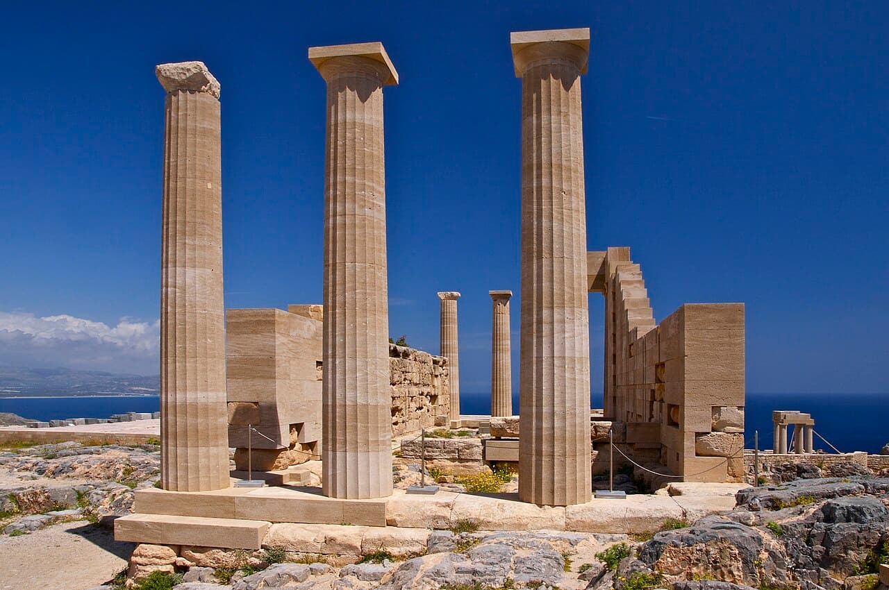 Columns of the Temple of Athena Lindia on the acropolis of Lindos, against a deep blue sky