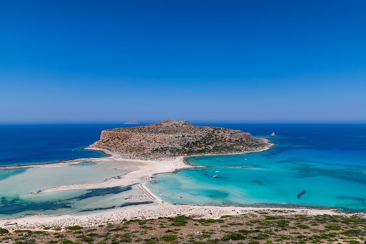 Aerial view of the turquoise shallows of Balos lagoon and the rocky cape in its centre
