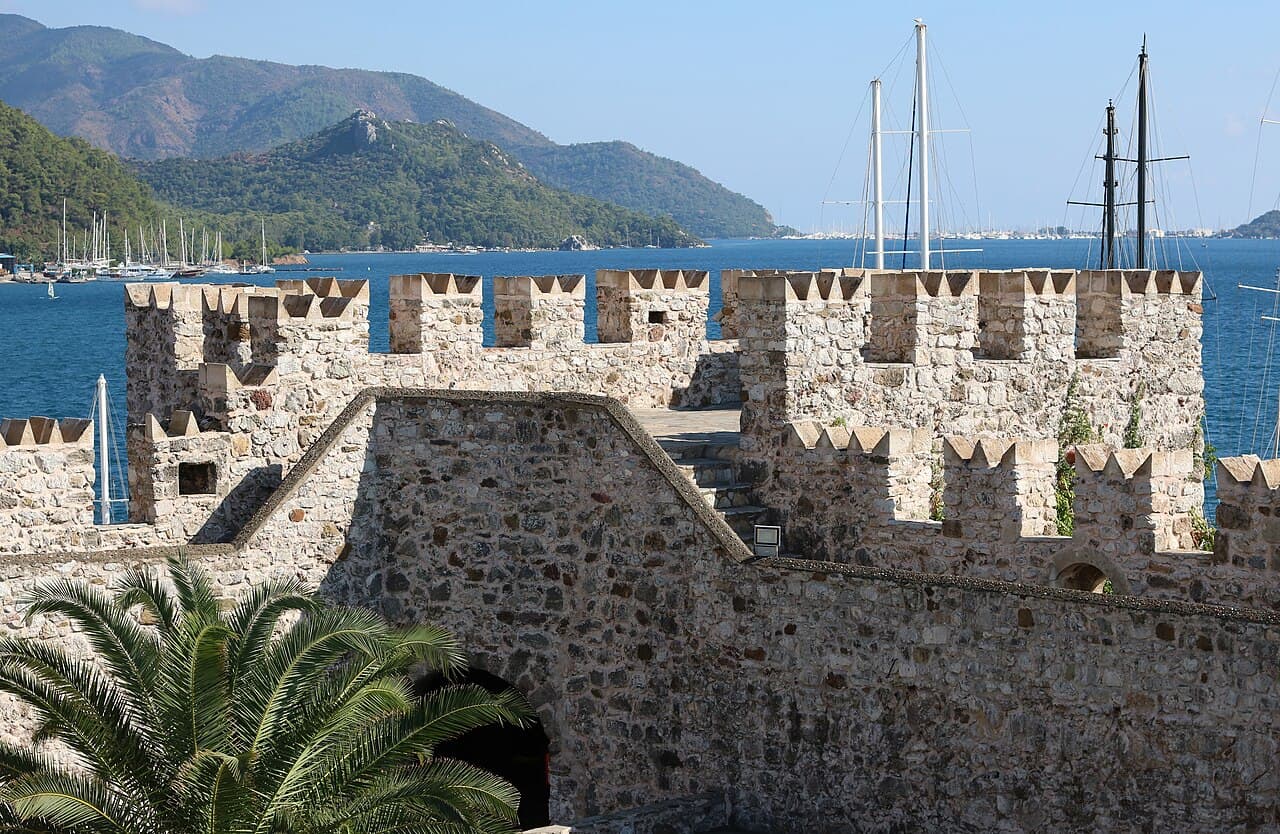 Stone battlements of Marmaris Castle, with the bay and wooded hills behind