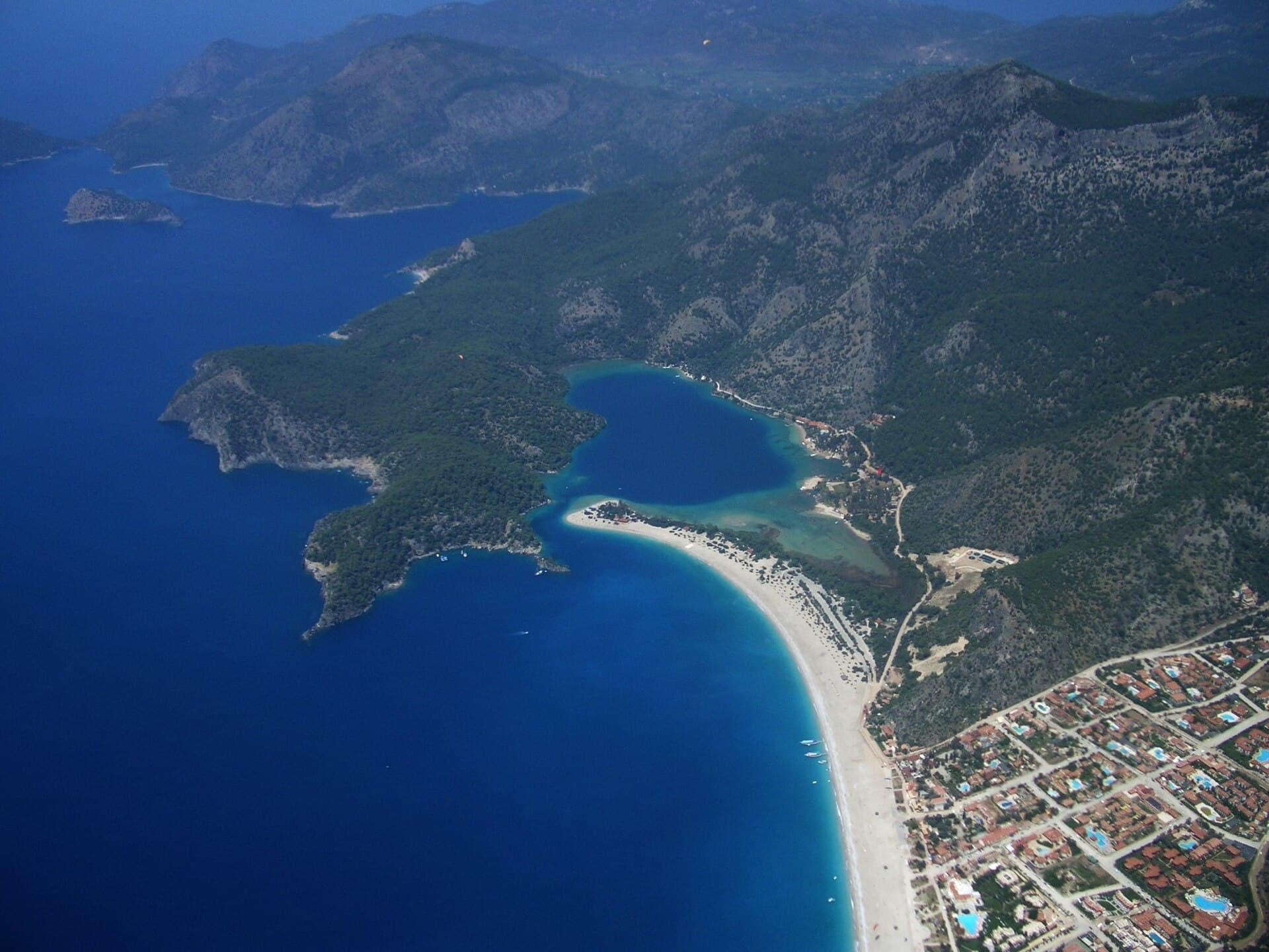 Aerial view of Ölüdeniz beach and the Blue Lagoon, with forested mountains running down to the sea