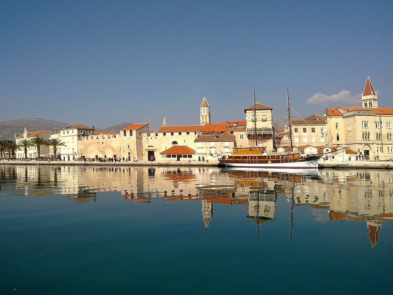 The stone waterfront of Trogir’s old town mirrored in still water